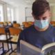 Studente con mascherina che legge in classe