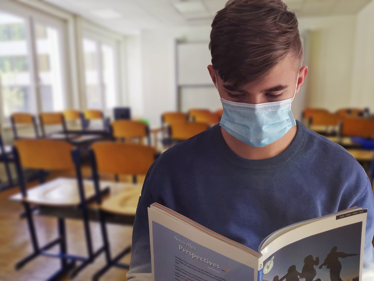 Studente con mascherina che legge in classe